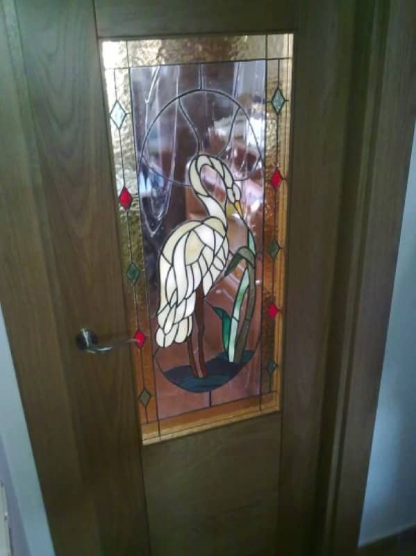Puerta de interior con una vidriera emplomada de una garza